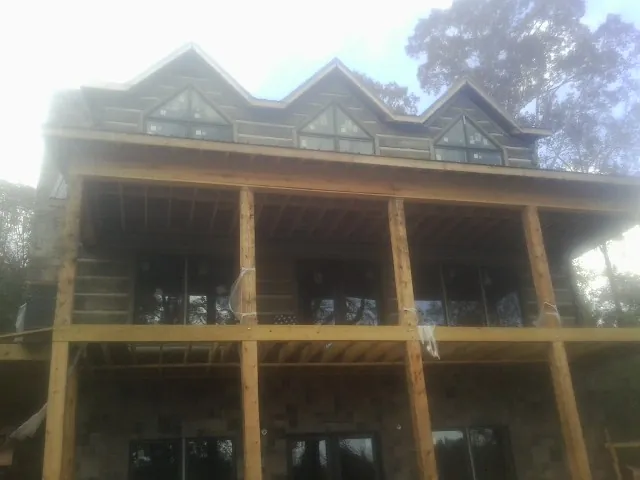 Dormers and porch framing on a large log home under construction — Roof Coating work by our crew in Cowansville