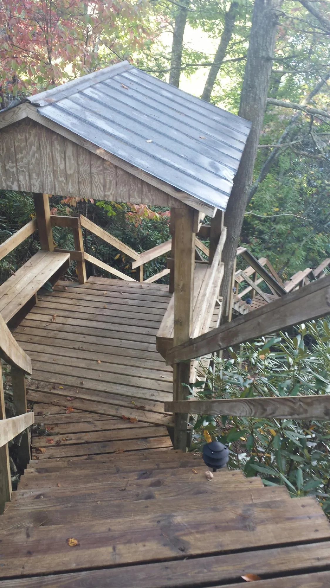 Metal roofed shelter over wooden steps on a wooded walkway — Skylight Repair & Installation work by our crew in Cowansville