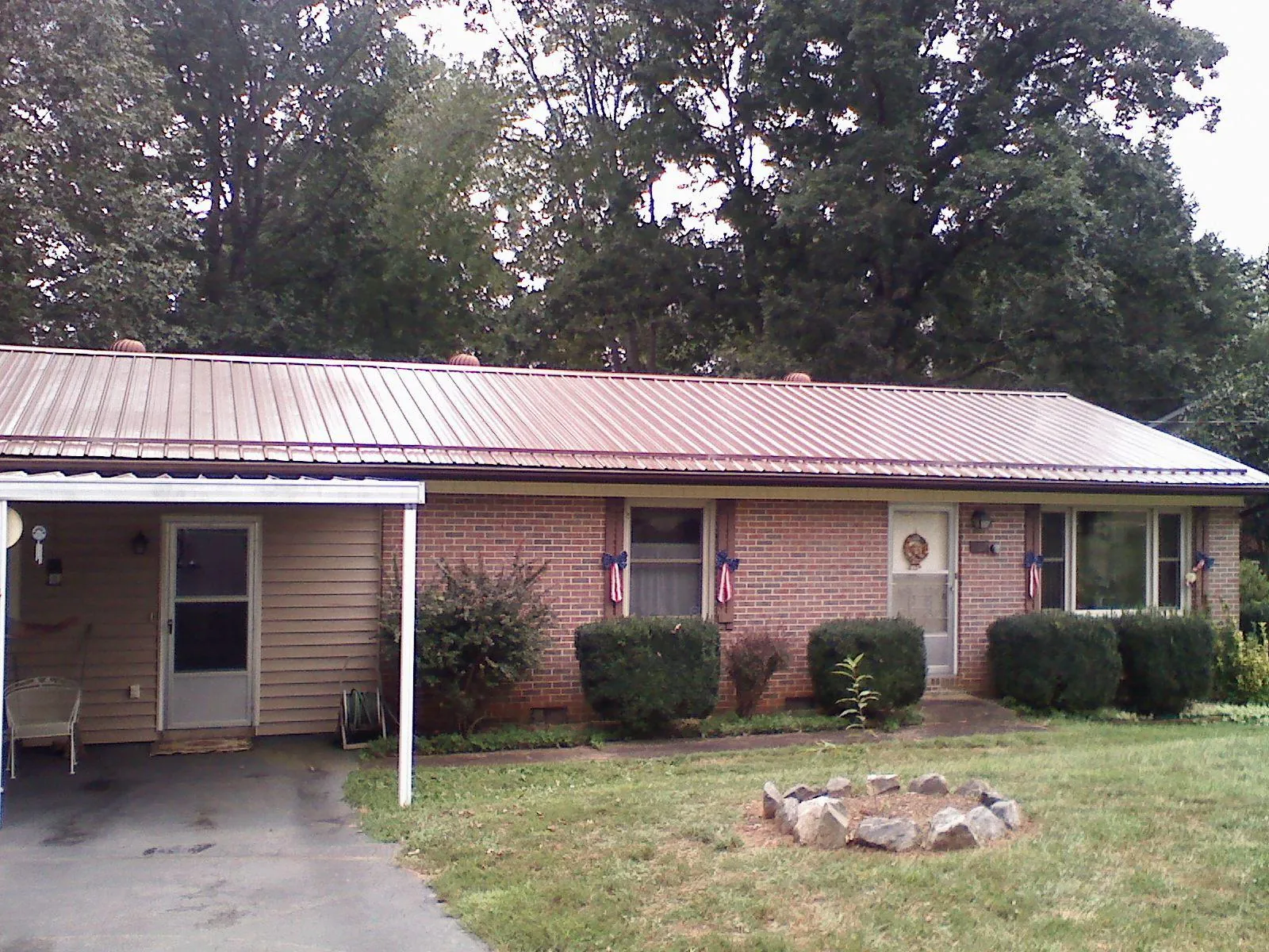 Bronze metal roof and carport on a brick ranch home — Roof Repair work by our crew in Cowansville