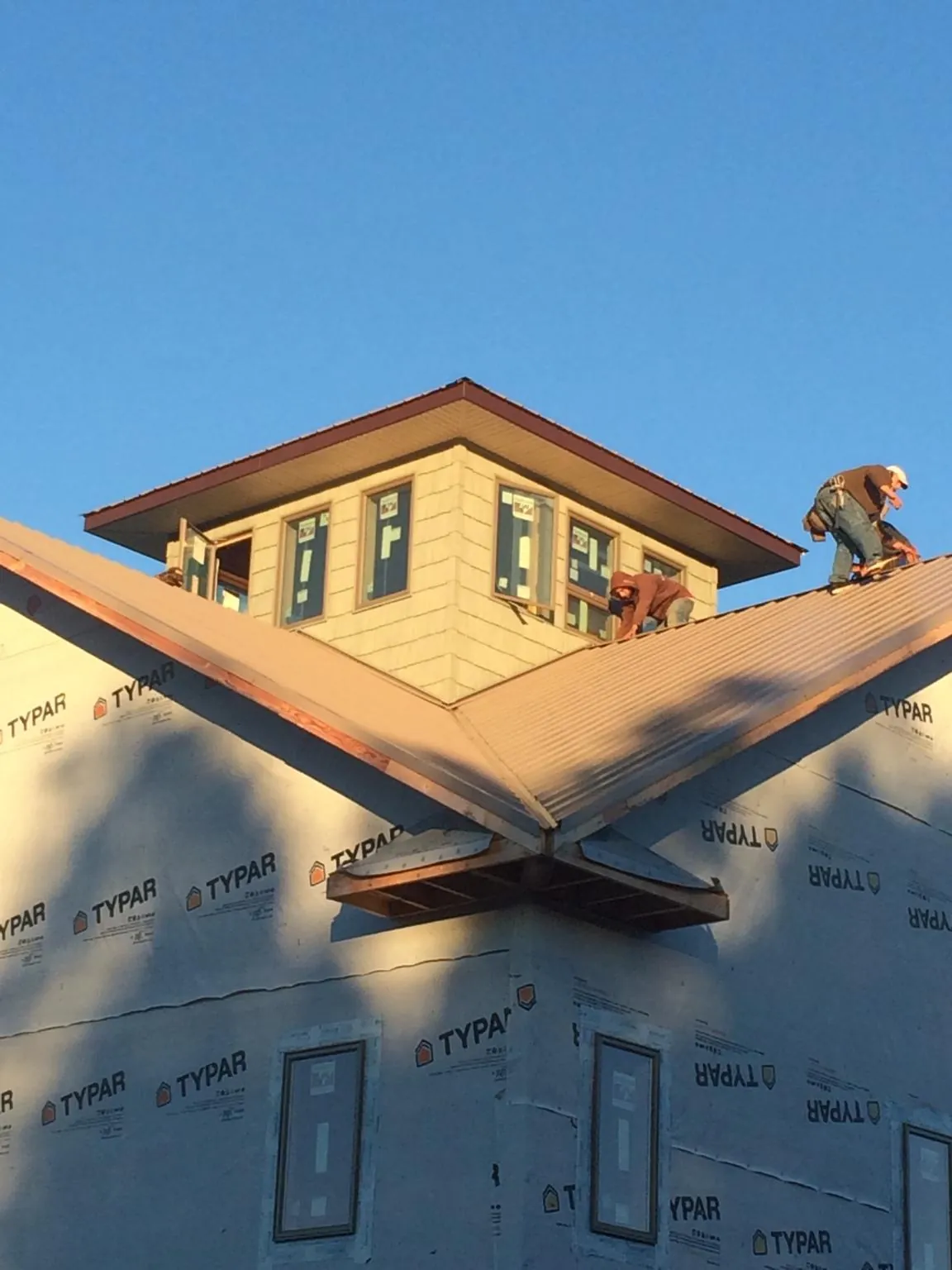Roofers working around a rooftop cupola on a new metal roof at sunset — Roof Waterproofing in Cowansville by Roofing Brothers